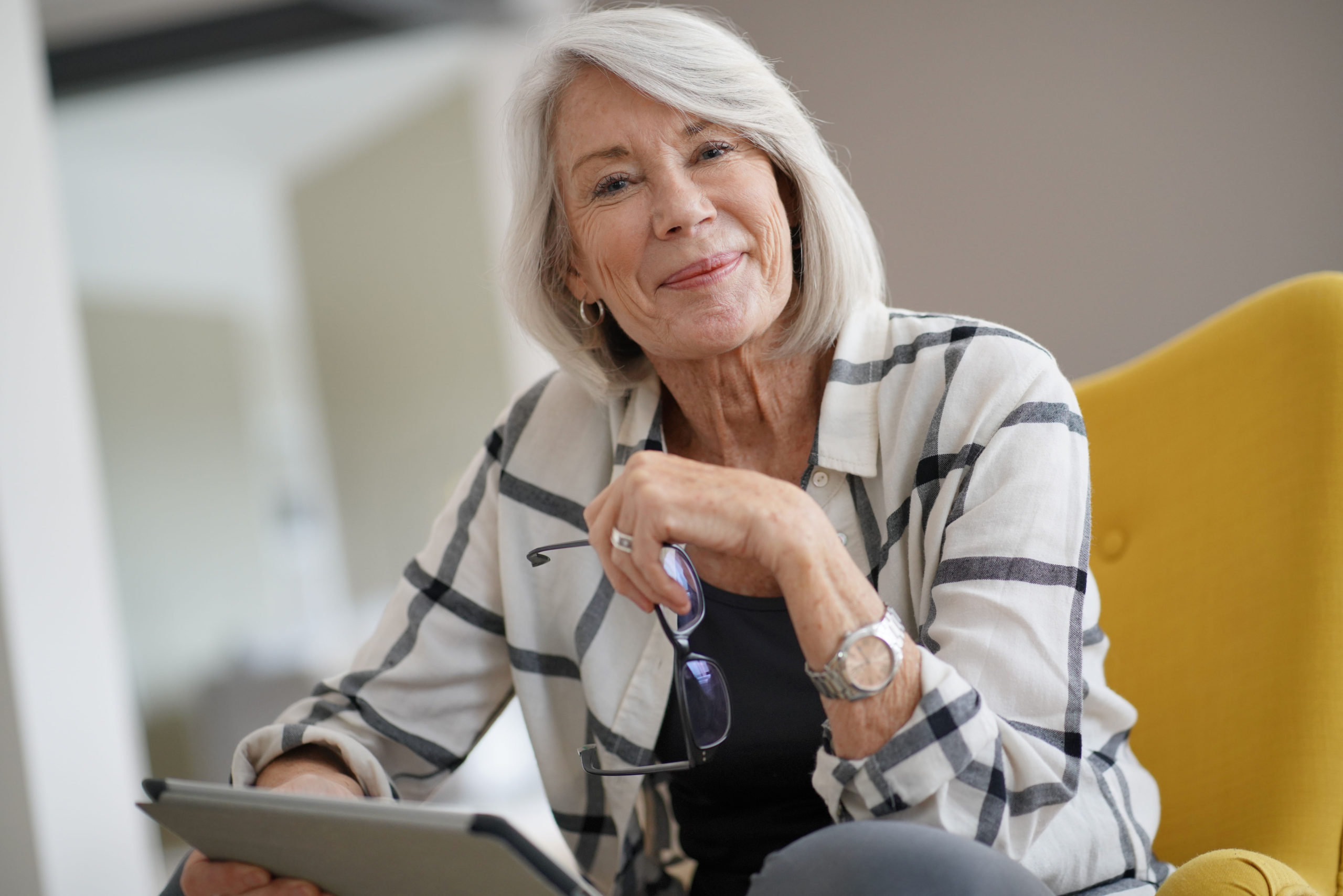 Stylish senior woman relaxing at home with tablet